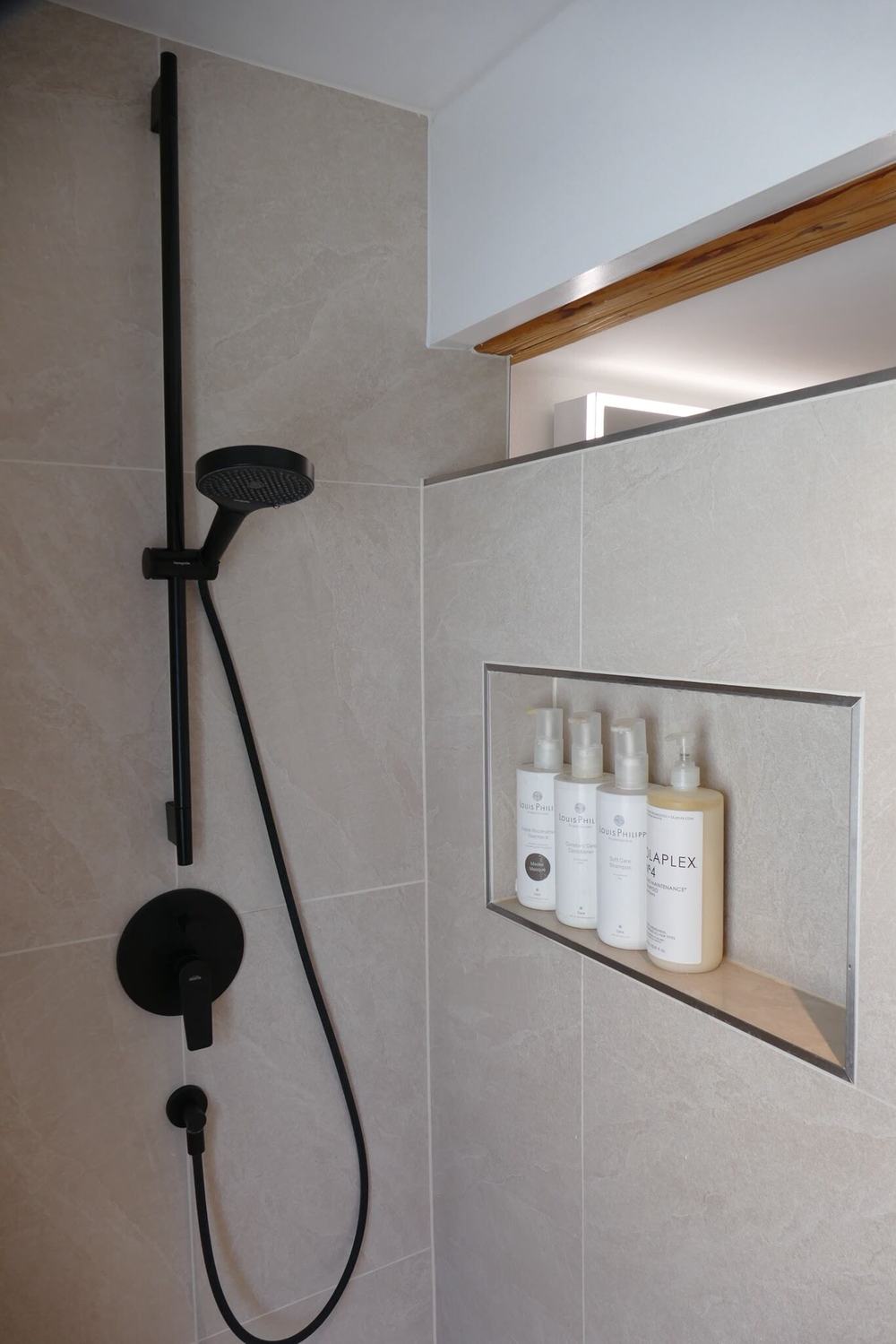 Geplättelte Dusche mit schwarzer Armatur und Wandnische