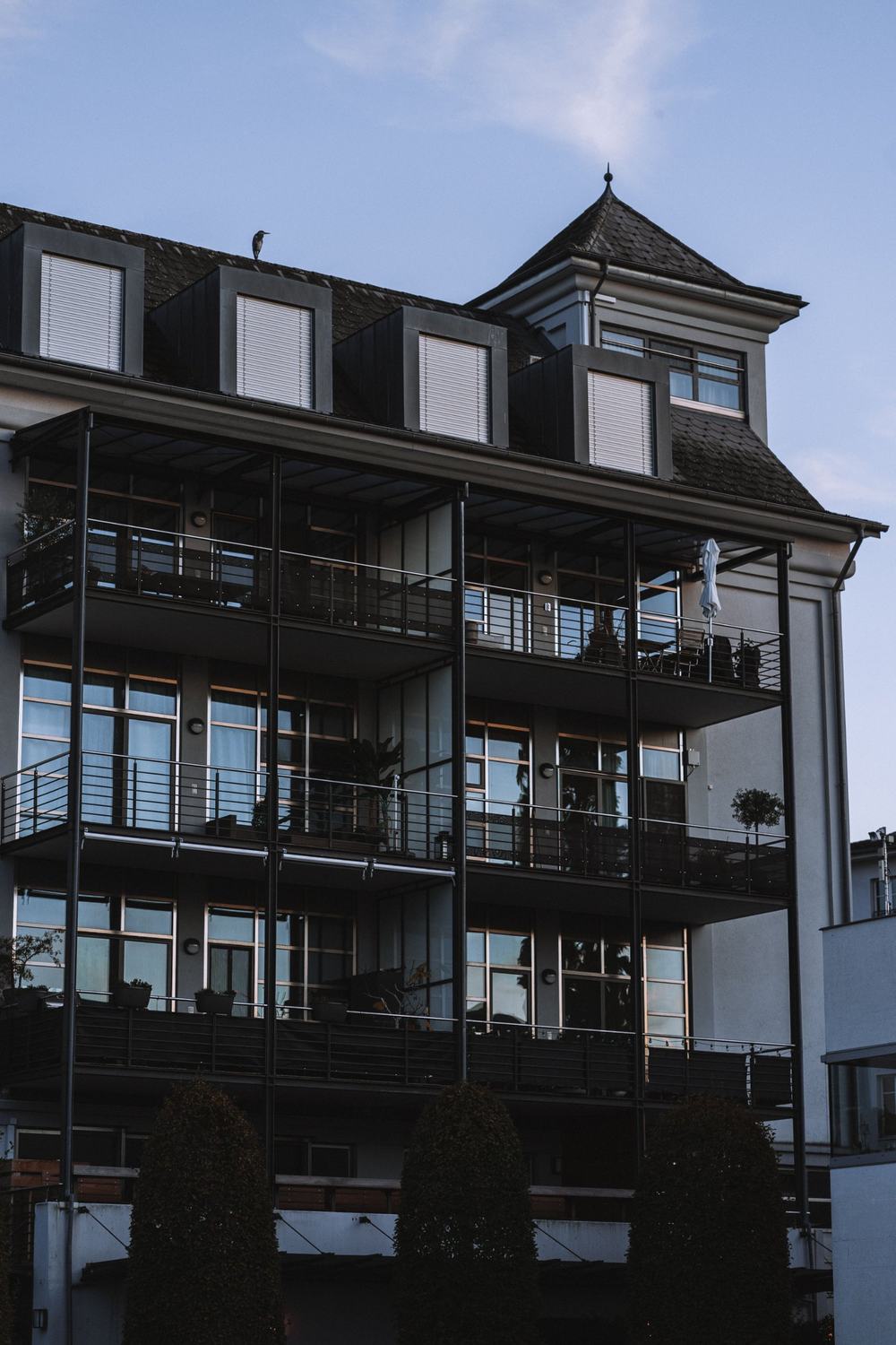 Mehrfamilienhaus mit Balkonen, Dachgauben und Türmchen in der Abenddämmerung
